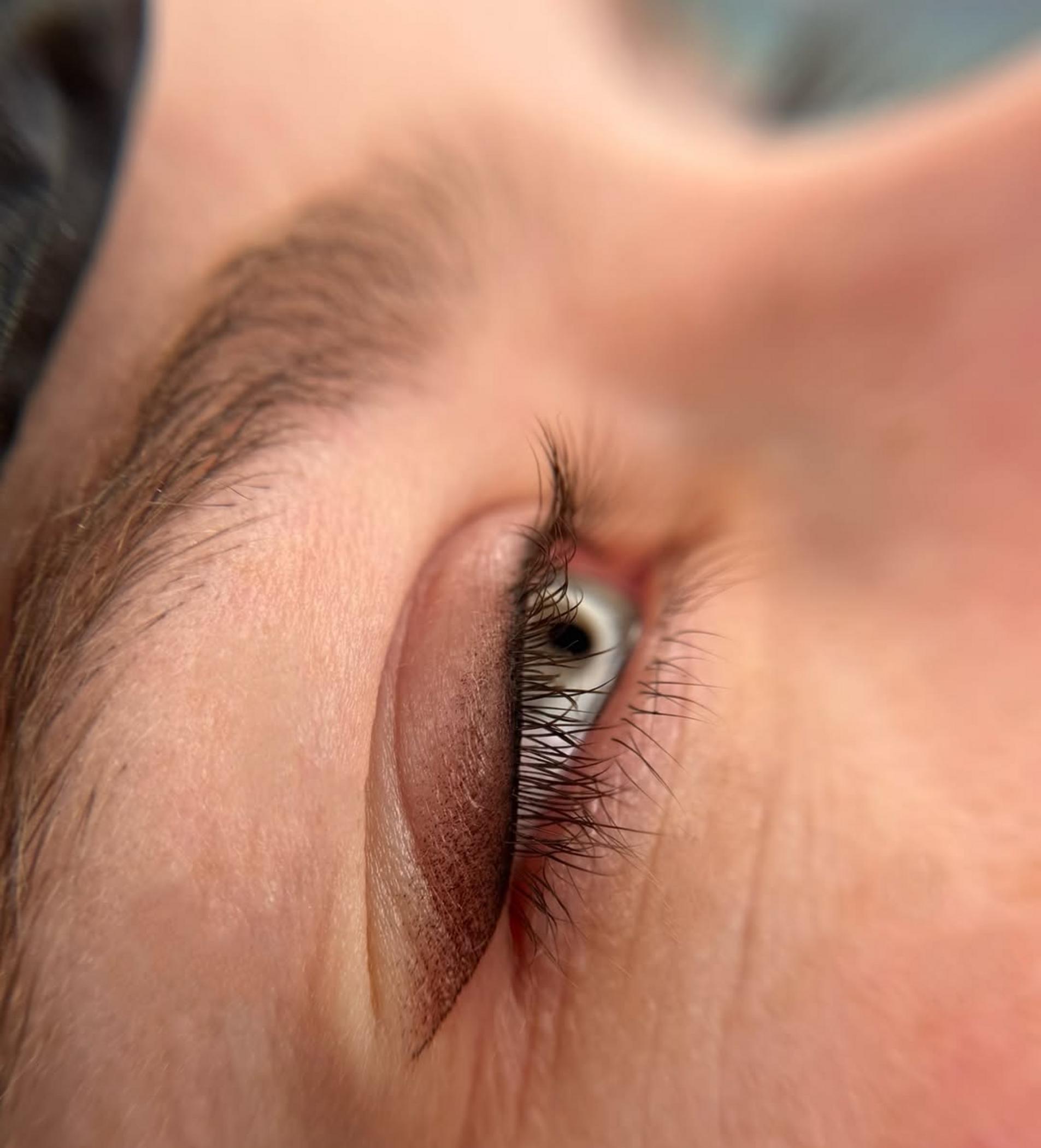 technician applying winged eyeliner tattoo